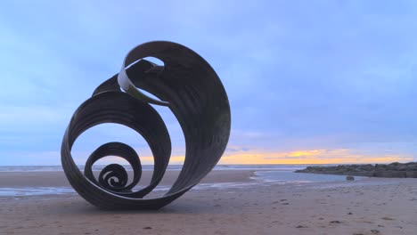 Stormy skies and incoming tide at beach with metal shell sculpture time lapse 60x at Mary&#039;s Shell, Cleveleys, Lancashire, England, UK