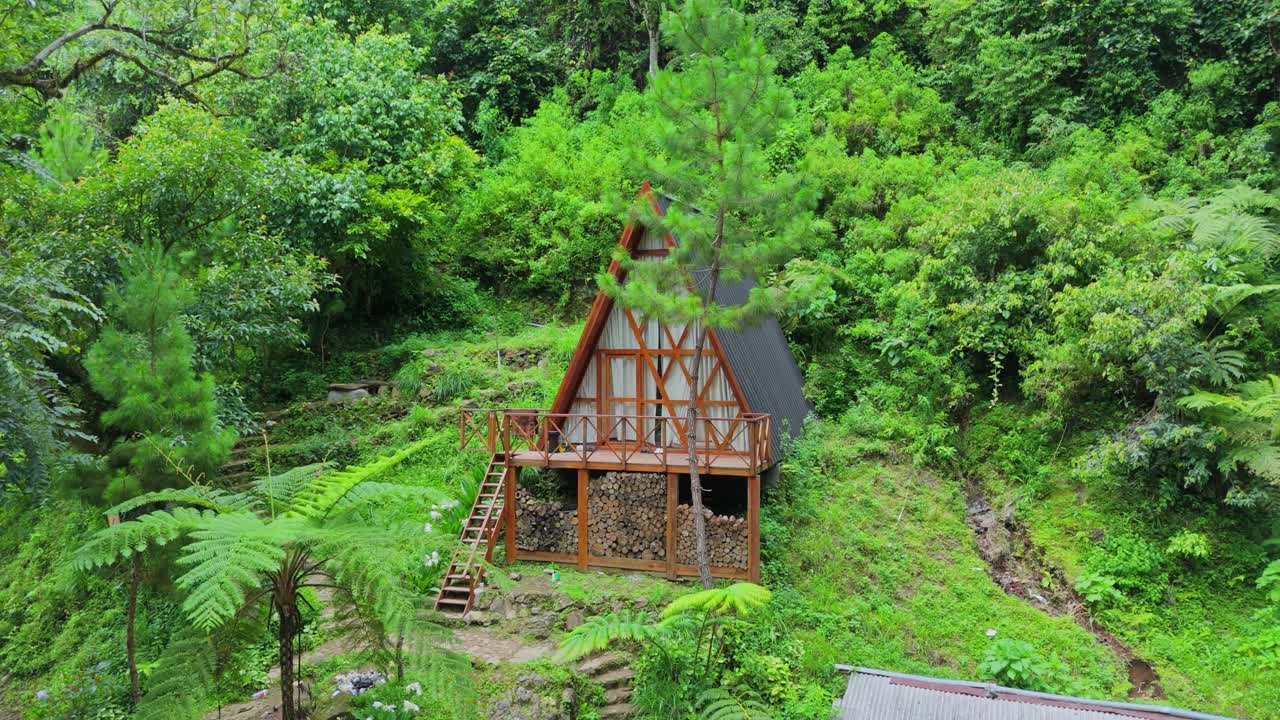 Baita in legno con tetto a capanna immersa in una lussureggiante collina di foresta tropicale