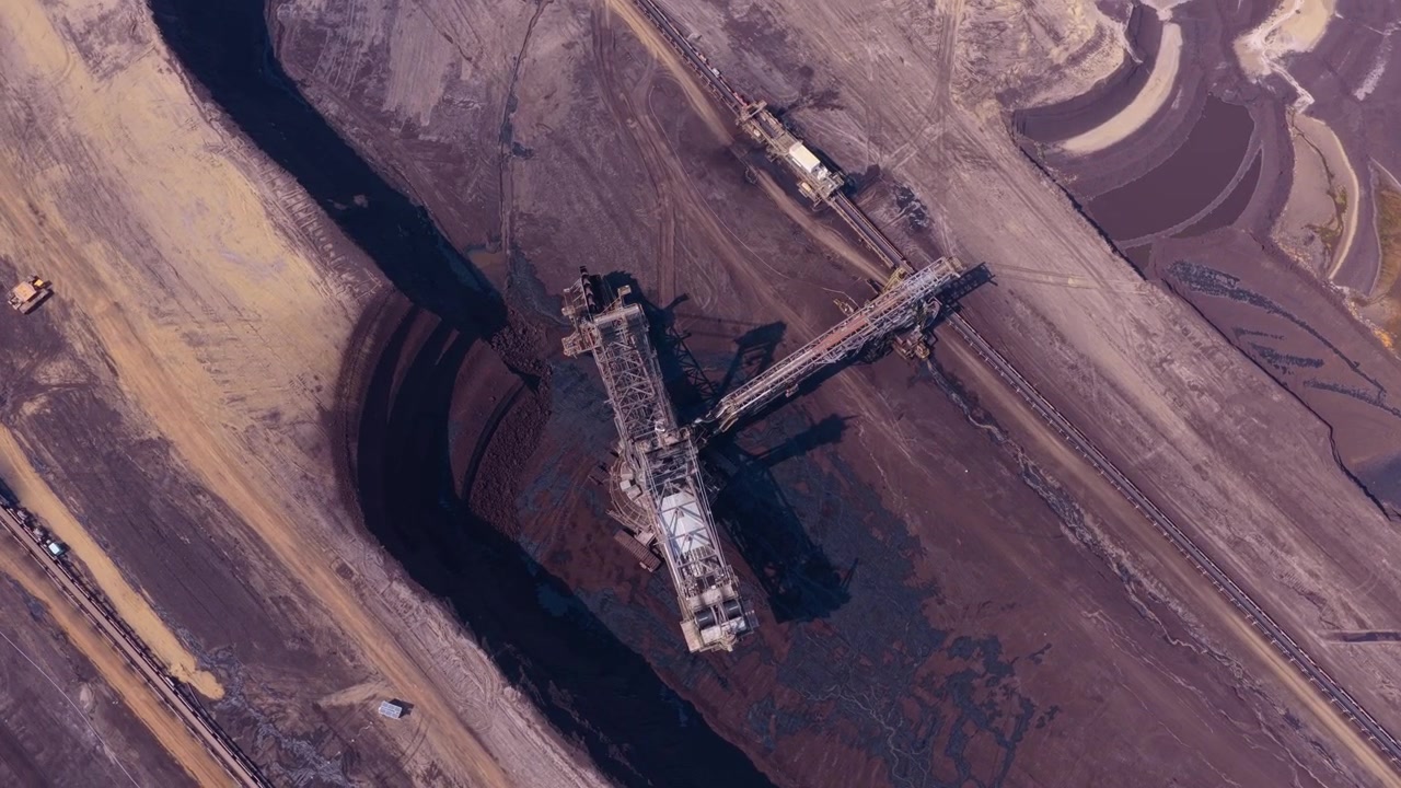Aerial top down view showing a massive bucket wheel excavator digging for lignite coal in a huge open cast mine in germany