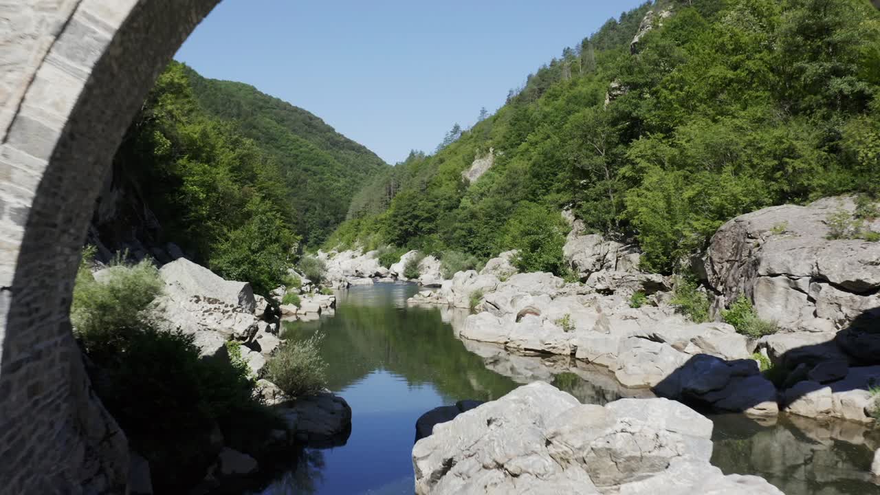 Approaching drone shot going through the Devil's Bridge over the Arda River located in the town of Ardino at the foot of Rhodope Mountain in Bulgaria.