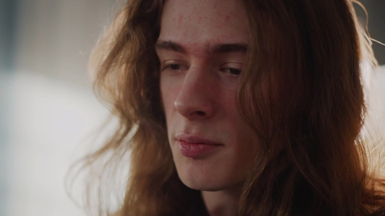 Male student receiving vocal lesson sunlight, sidelit closeup showing expressive mouth and steady breath, mentor feedback implied through attentive posture, classroom loft with window backlight, calm