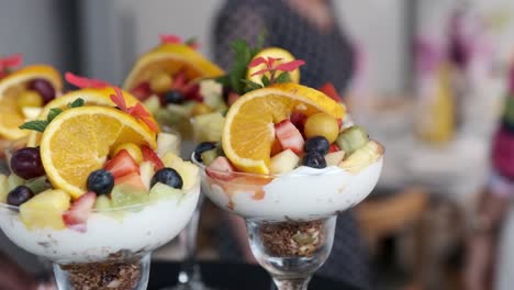 healthy breakfast fruits and berries with greek yogurt and granola being served in a glass on a tray