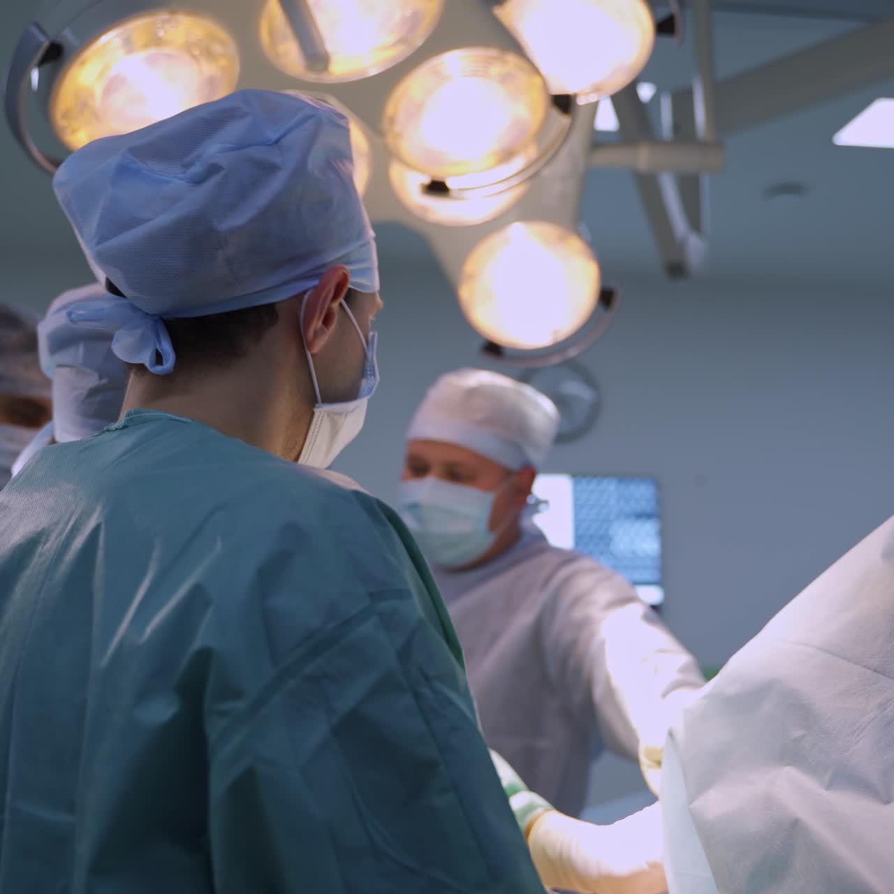 Medical professionals team working under the lamps in surgery room. Surgeons collaborating at operation