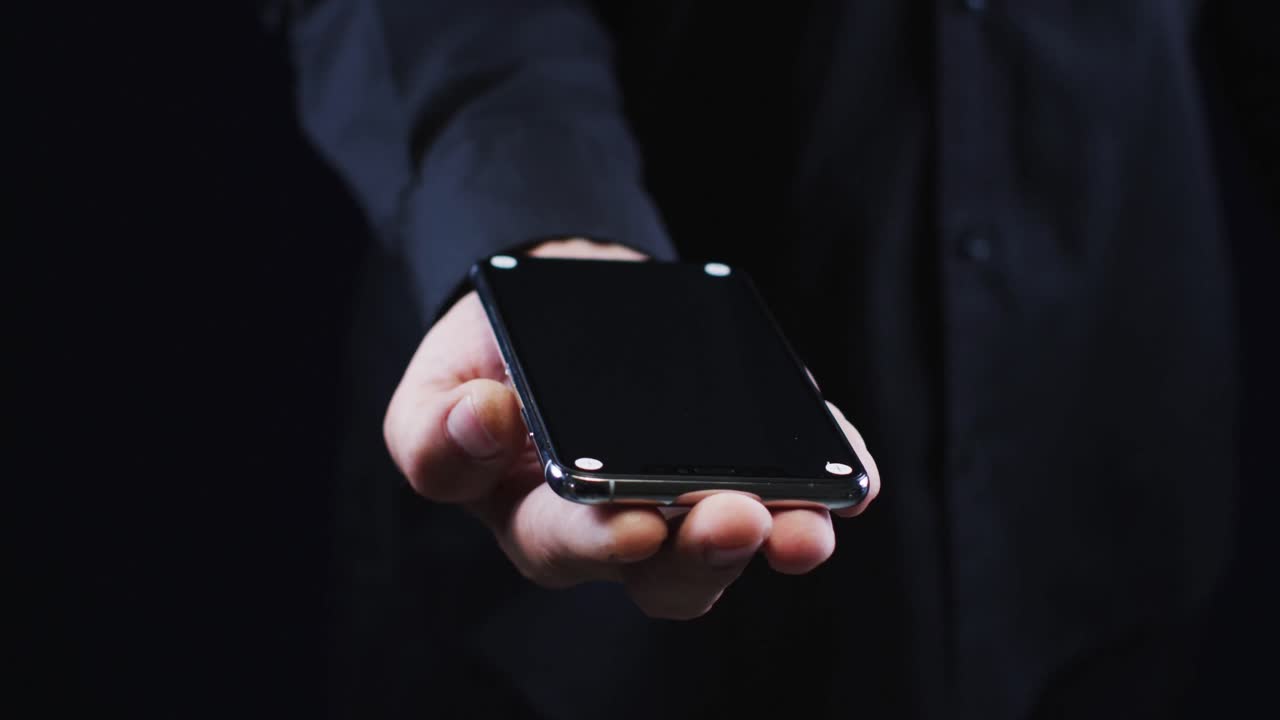 스마트폰을 들고 있는 검은 셔츠를 입은 백인 남자의 손