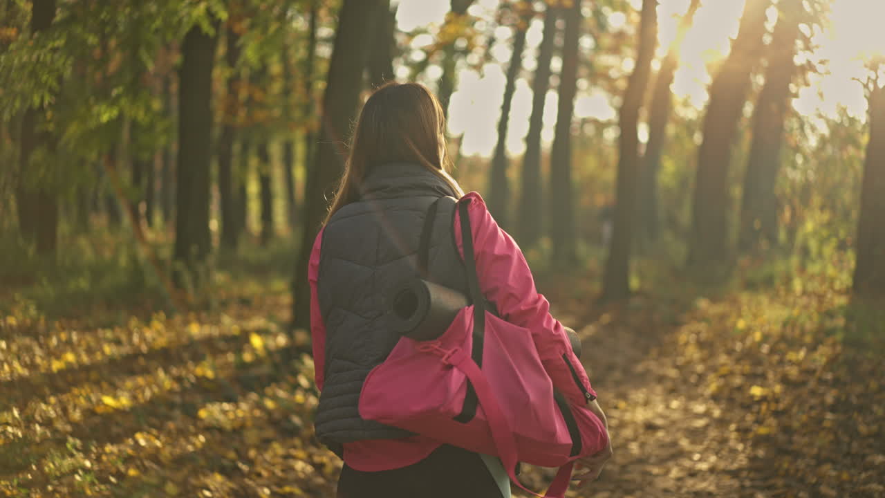 Woman Walking in Autumn Park with Yoga Mat