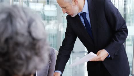 businessman giving a document to colleague