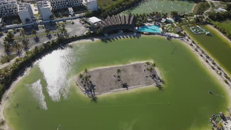 aerial orbit shot of caribbean lake park with tropical island, hotel resort, swimming pool and exotic vibes. sunny day in punta cana town, dominican republic. orbit view.