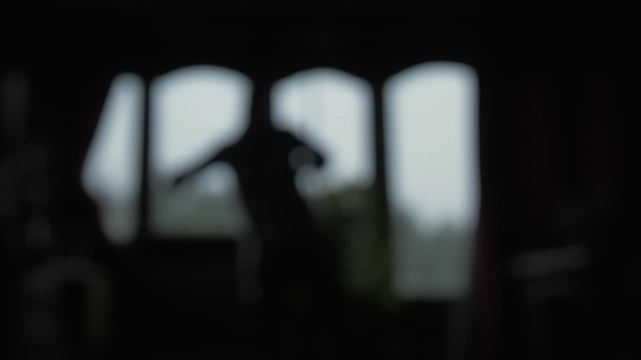 남자가 창문을 드러내는 커튼을 열고 보케가 흐릿해집니다.