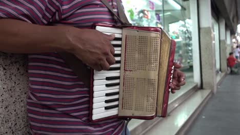 Un-Músico-Callejero-Toca-El-Acordeón-Frente-A-La-Ventana-De-Una-Zapatería-En-Un-Centro-Comercial