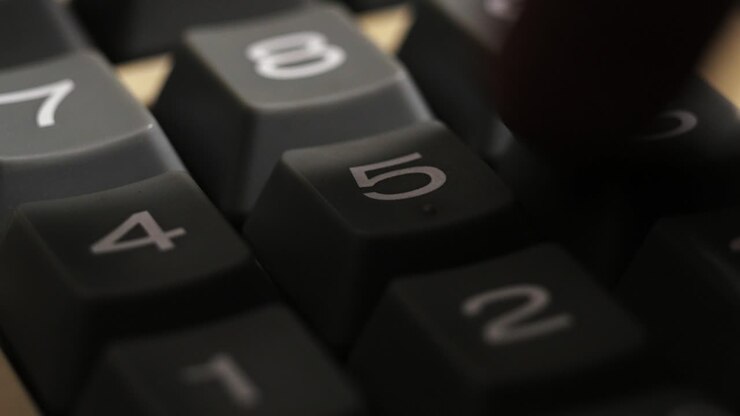 Close up of fingers pressing number keys on a vintage calculator while entering calculations