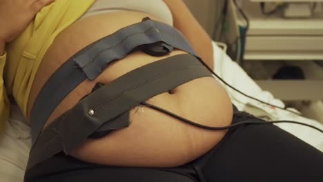 Pregnant-female-belly-strapped-in-to-the-monitor-to-check-the-baby