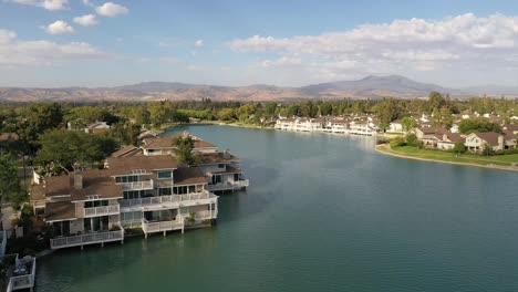 drone flying over woodbridge north lake over houses, with blue skies, green lake, and sunny 2022 summer day