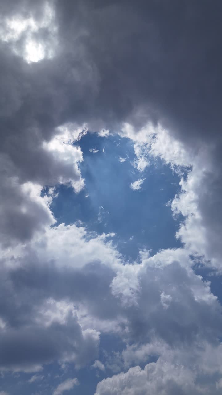 A blue cloudless spot between the clouds with sunlight shining through, creating a calm scene.