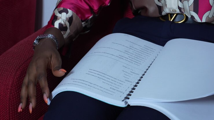 Spiral bind book or large document with black woman's hands turning the pages