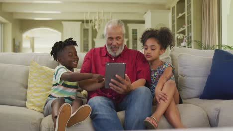 grandfather and grandchildren using digital tablet at home