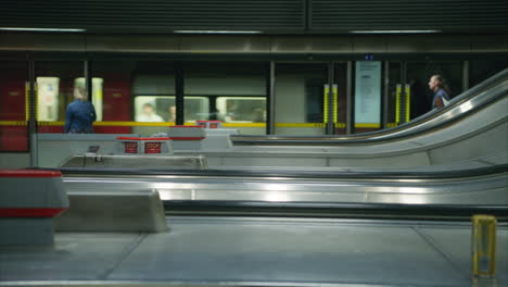 eine frau auf dem bahnsteig eines u-bahn-stations in london, die auf einer rolltreppe steigt, in echtzeit erschossen.