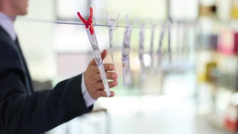 a person's hand handling dollar bills hung on a line, symbolizing money laundering