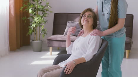 Senior-Woman-Sitting-On-A-Sofa-And-Female-Doctor-Putting-Hands-On-Her-Shoulders