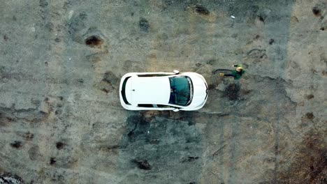 Hombre-Entrando-En-Una-Vista-De-Arriba-Hacia-Abajo-De-Un-Coche-Eléctrico-Blanco