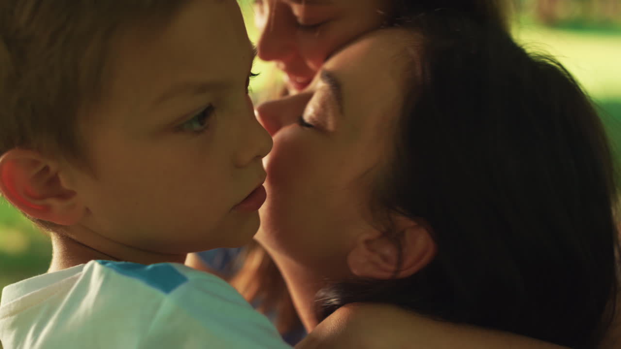 Madre affettuosa bacia il figlio durante un picnic, primo piano. Donna felice che mostra amore ai bambini.