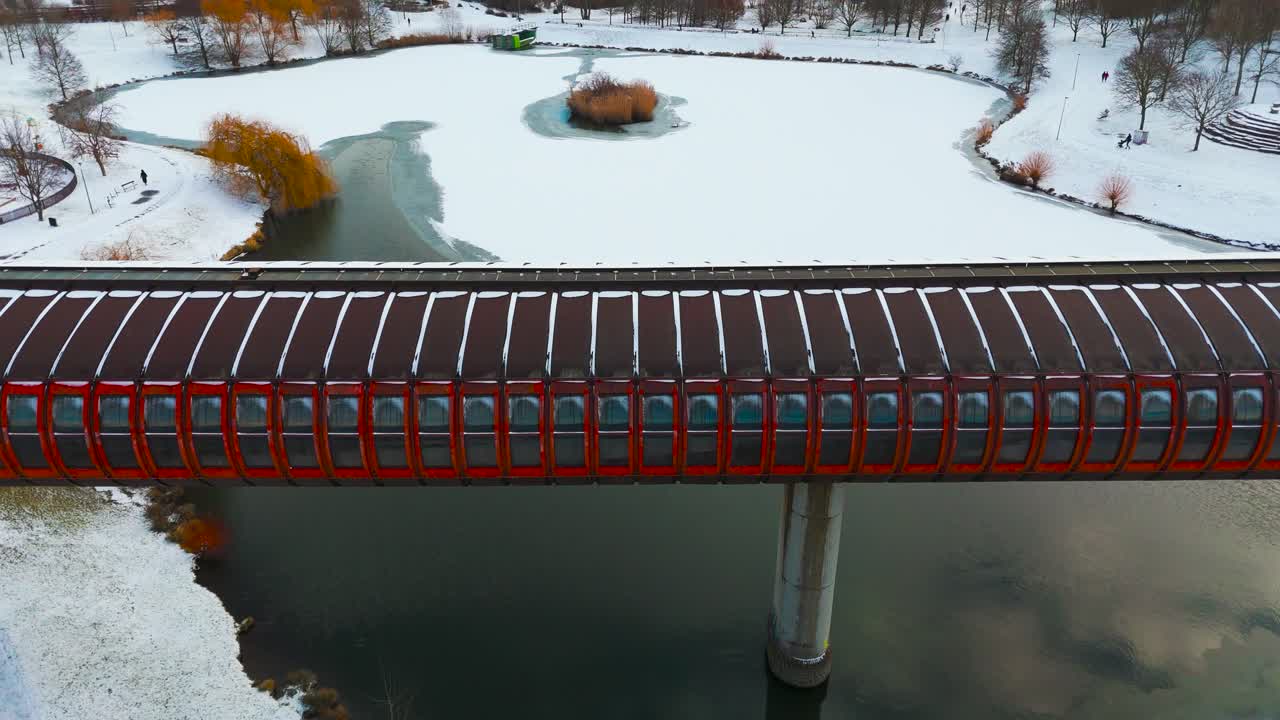 Hurka Luziny Metro Bridge crossing over frozen pond in snowy park, Prague