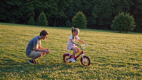 father teaching daughter to ride a bicycle in a park