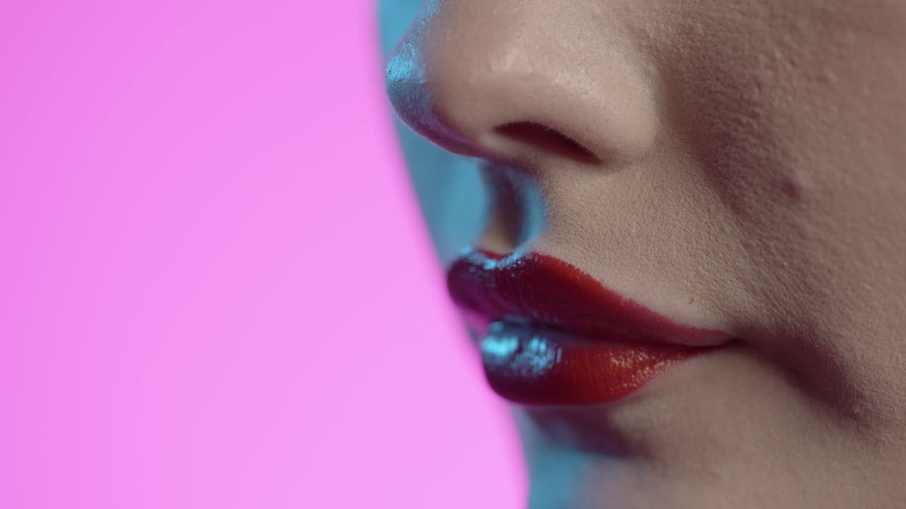 mujer laméndose los labios, lápiz labial rojo, fondo rosa