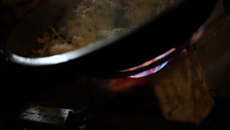 foto de un vendedor ambulante cocinando su comida indonesia para venderla en una olla sobre una llama