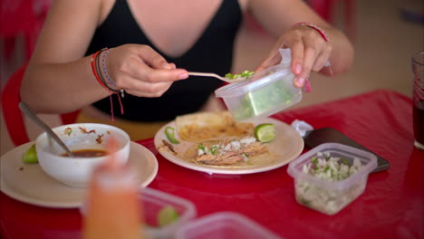 Cierre-En-Cámara-Lenta-De-Una-Mujer-Latina-Preparando-Su-Taco-De-Barbacoa-Con-Chile-Verde-Picado-En-Un-Restaurante-En-México