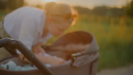 close-up of woman caring for baby in stroller at sunset