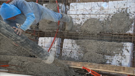 Tilt-down-view-of-a-mexican-latin-construction-worker-applying-concrete-mix-on-top-of-a-grid-with-styrofoam-to-make-the-flooring-slab-of-new-house-in-Mexico