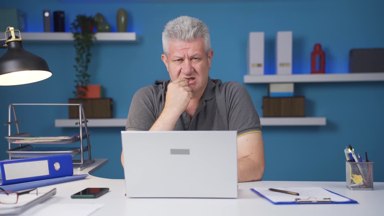 trabajador de oficina en casa mordiéndose las uñas mirando a la cámara.