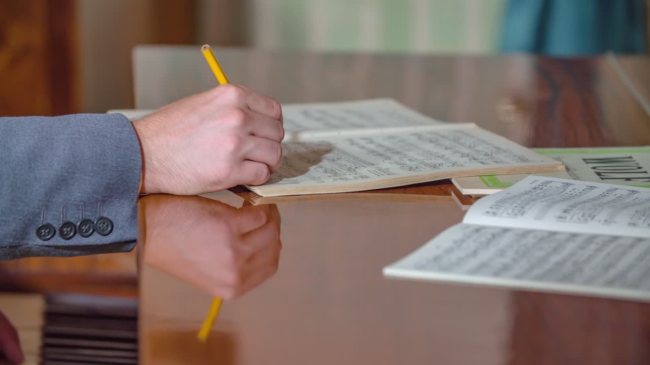 Caucasian hand composing musical arrangement with pencil sitting by piano, close up static