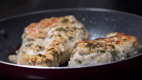 steaming chicken breasts cook on a pan covered in bubbling oil coating the dinner time meal with a crispy texture and seasoned with rosemary, food rack focus closeup