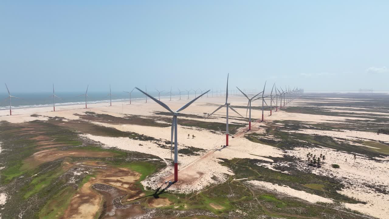 Wind turbines on sandy beach of Delta do Parnaíba, vast coastline with clear sky