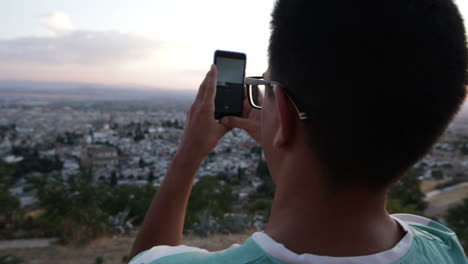 person taking photo of city at sunset