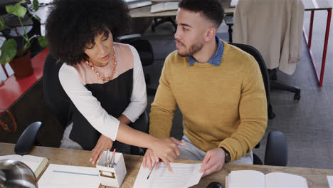 Diverse-male-and-female-colleagues-sitting-at-desk,-looking-at-computer-and-talking,-slow-motion