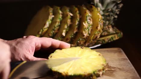 male slicing comosus pineapple ananas with a knife