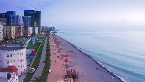 Volando-Sobre-El-Paseo-Marítimo-Y-La-Zona-Turística-De-La-Moderna-Ciudad-Costera-Al-Amanecer