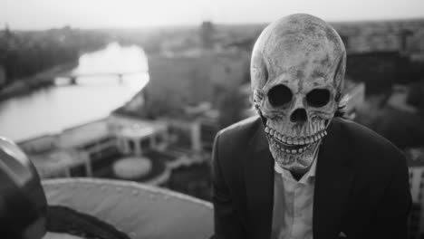person in skull mask on rooftop overlooking city