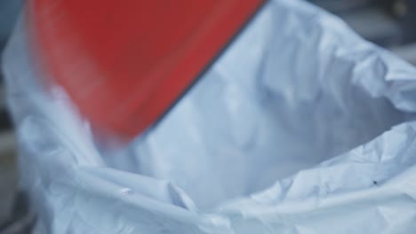 person throwing trash from dustpan in a sack