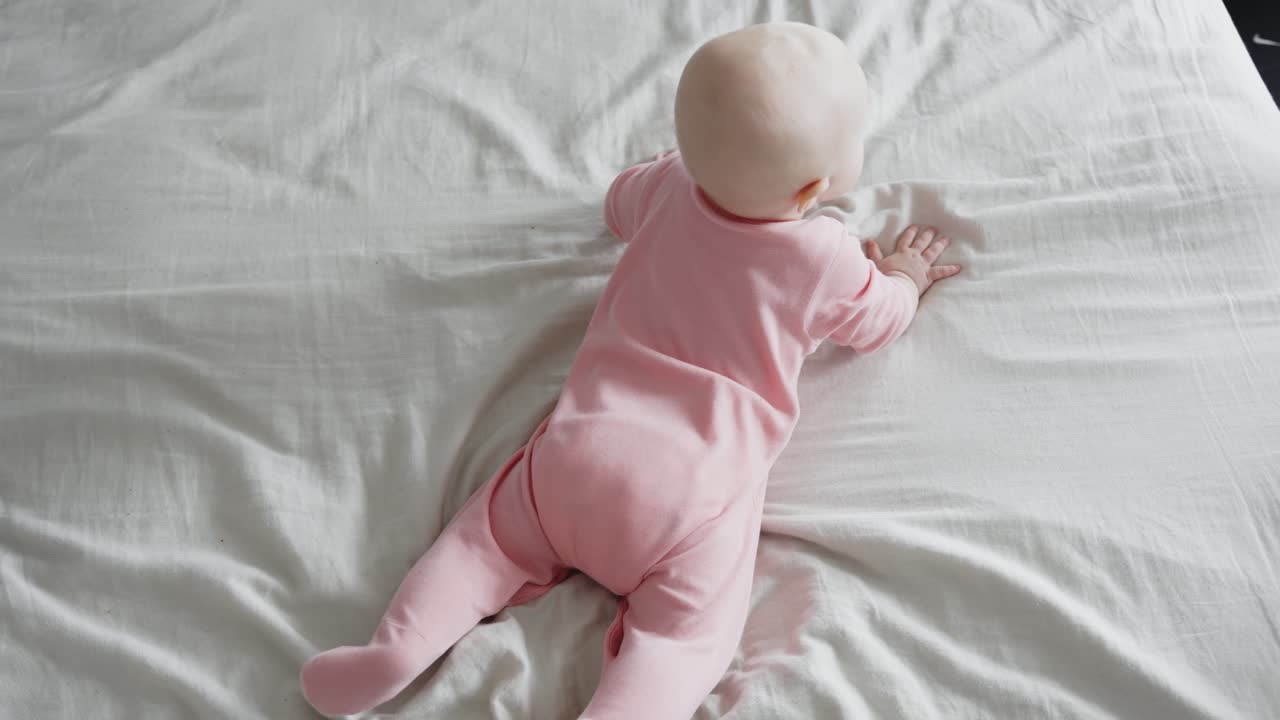 Bambino di sette mesi che impara a gattonare sul letto e si alza a quattro zampe.