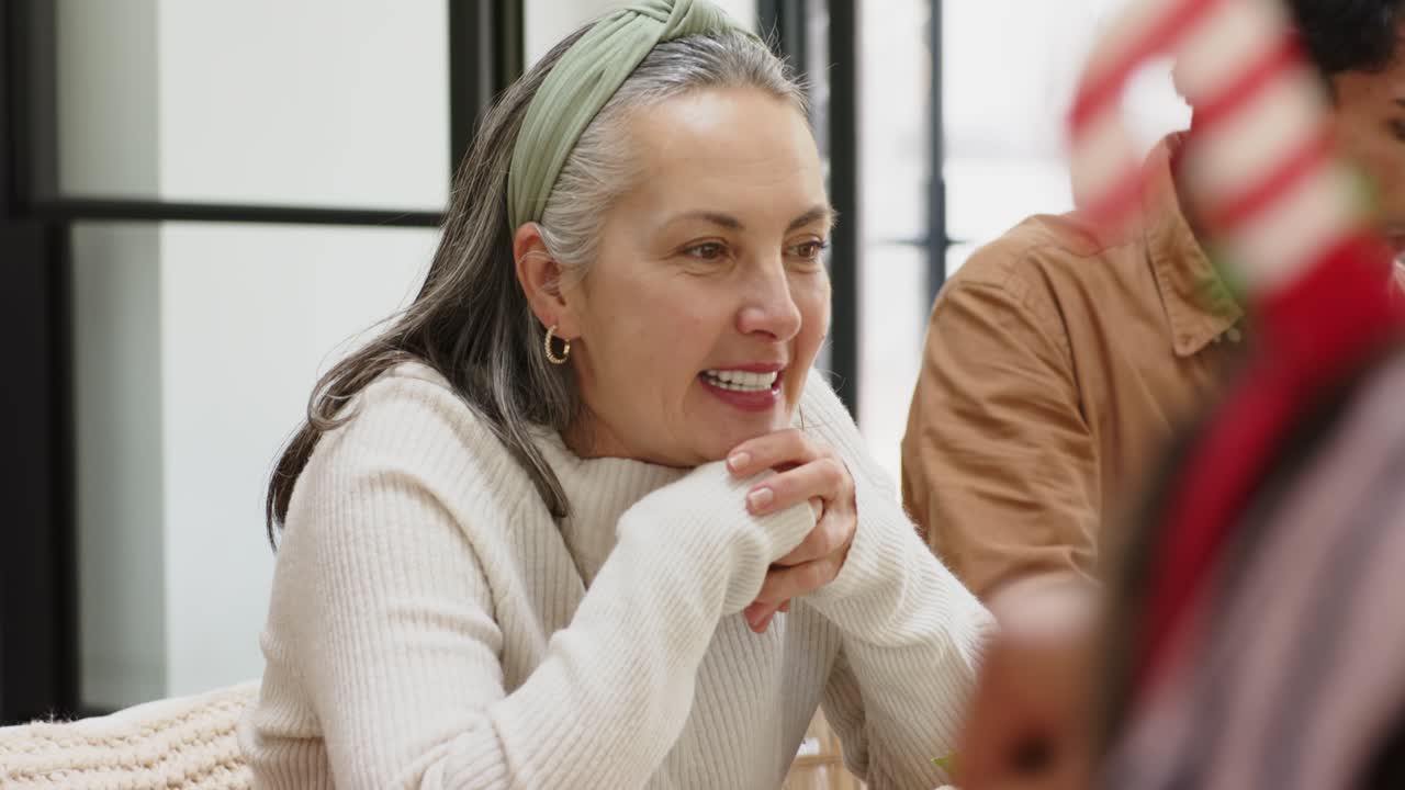 Coworkers discussing ideas over salad while woman leaning on hands speaking and man sipping water