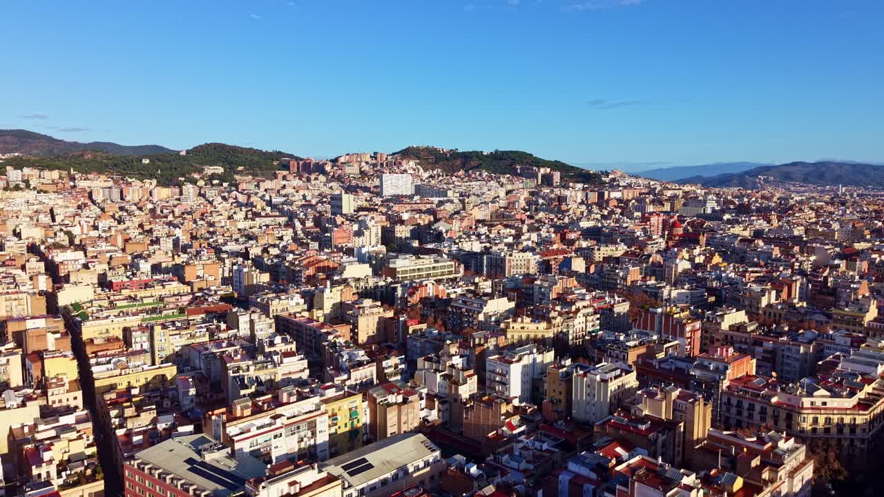 Vue aérienne cinématique prise par drone de la ville tentaculaire de Barcelone par une journée ensoleillée. Le paysage urbain dense se détache sur fond de collines et d’un ciel bleu clair, Espagne