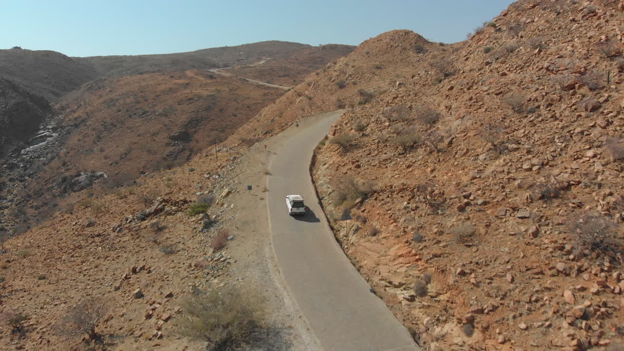 seguimiento aéreo coche conduciendo por una carretera estrecha cuesta arriba
