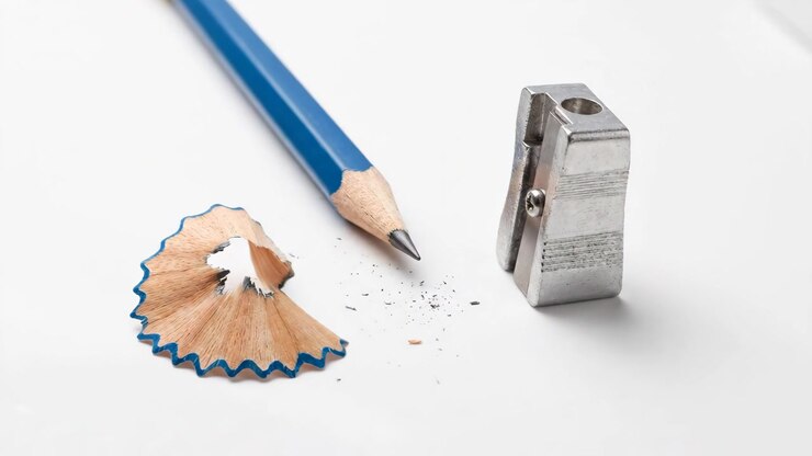 Blue Pencil and Metal Sharpener with Wood Shavings on White Background