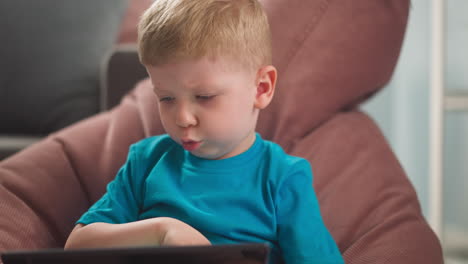 Adorable-toddler-boy-plays-video-game-sitting-in-bean-chair