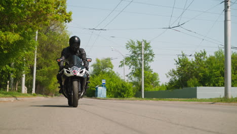 driver in helmet rides motorcycle along wide empty road