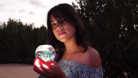 A beautiful mysterious woman with a magic glowing crystal ball in an enchanting fantasy land
