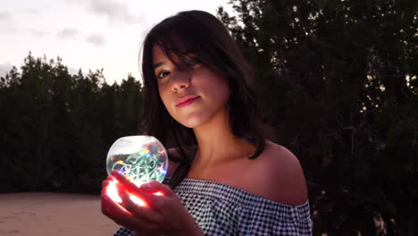 una hermosa mujer misteriosa con una mágica bola de cristal brillante en una tierra de fantasía encantadora